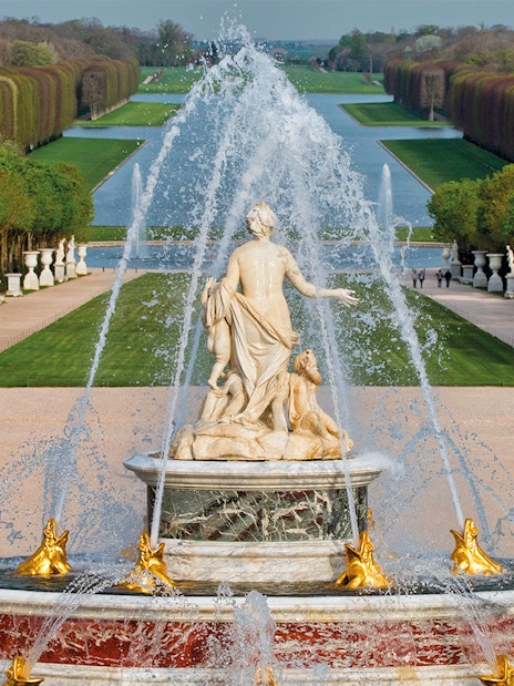 Fountain with statues and water jets at the Palace of Versailles, Paris.