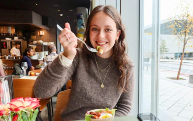 Dining experience on Oslo Small-Group Walking Tour, woman enjoying meal in a local restaurant.