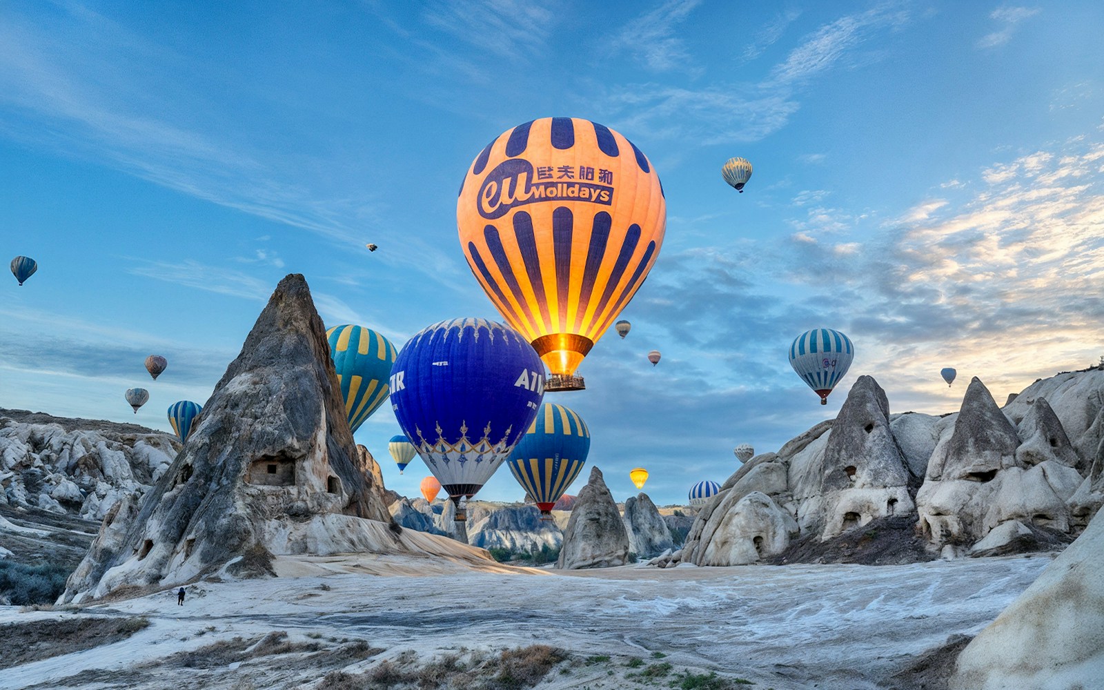 Hot air balloons floating over rock formations in Gerome Valley, Cappadocia.