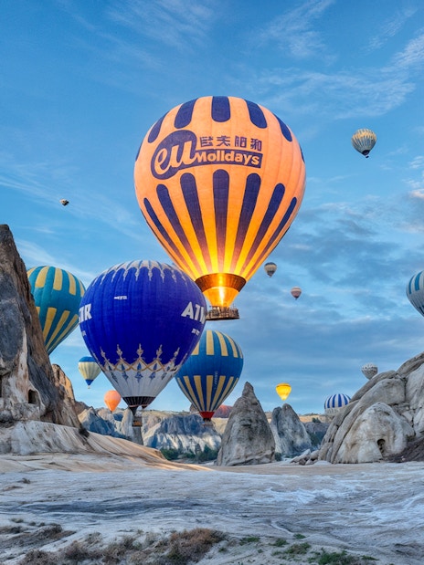 Hot air balloons floating over rock formations in Gerome Valley, Cappadocia.