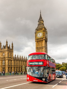 Red double-decker bus near Big Ben and Houses of Parliament, London HOHO tour.