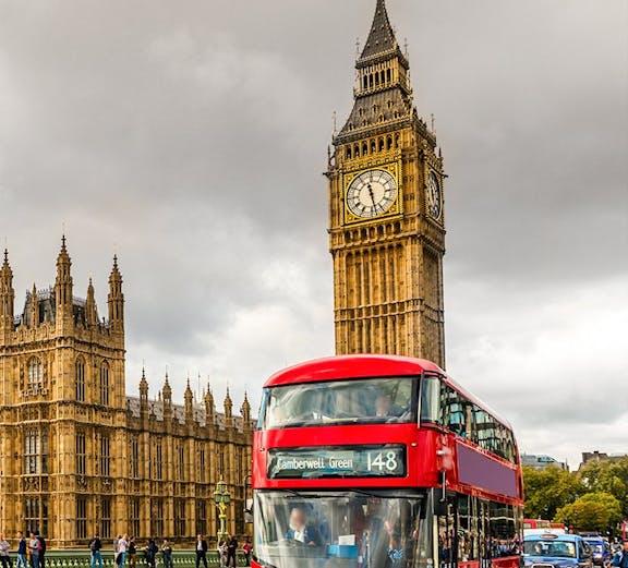 Red double-decker bus near Big Ben and Houses of Parliament, London HOHO tour.