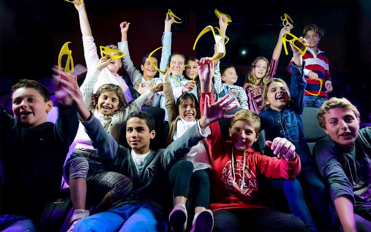 Children enjoying Malta 5D audio-visual show with 3D glasses in hand.