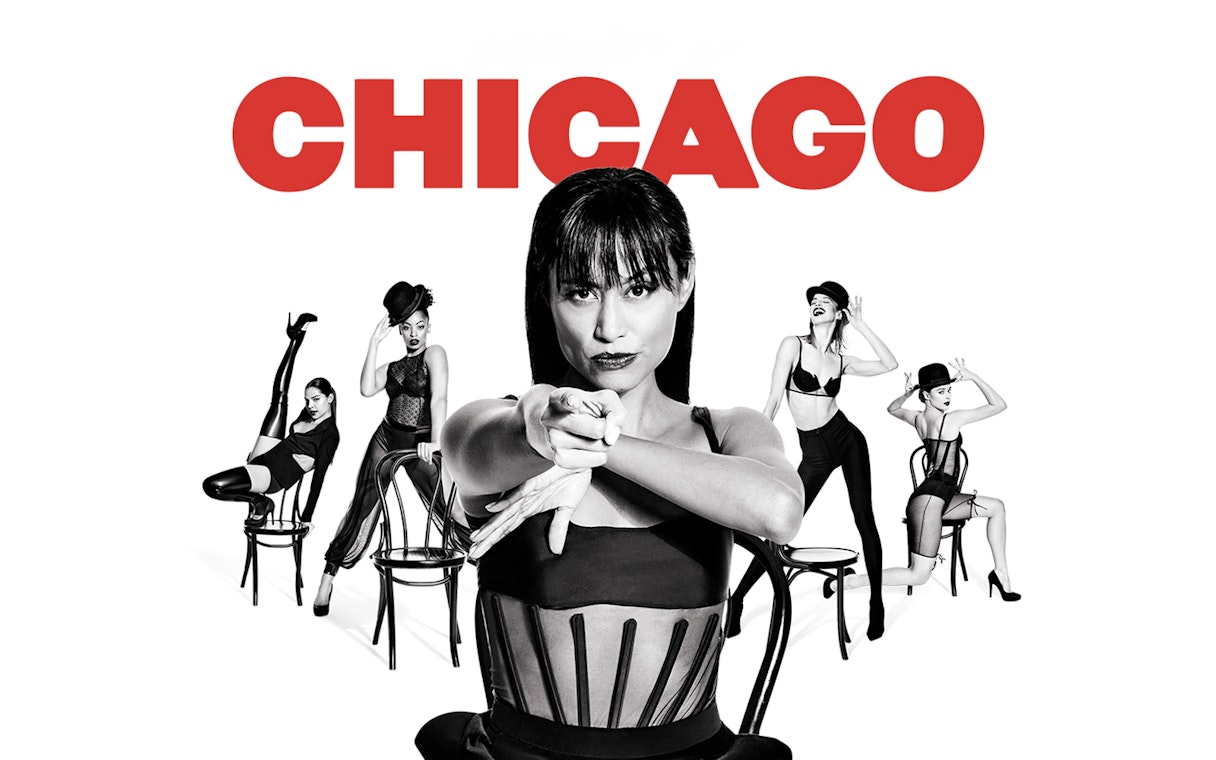 Performers in black costumes with chairs, promoting the musical "Chicago.