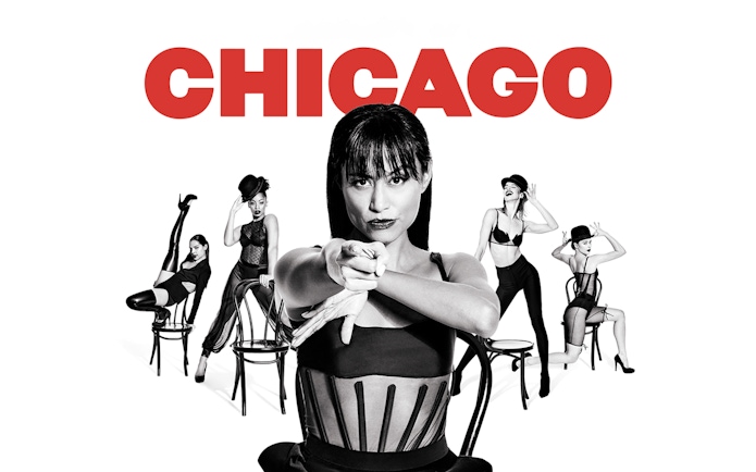Performers in black costumes with chairs, promoting the musical "Chicago.