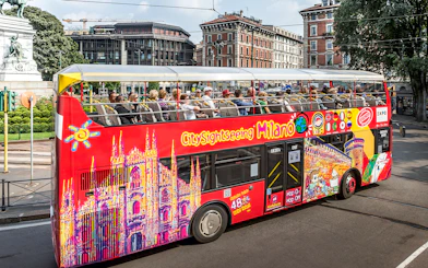 City Sightseeing bus with tourists in Milan near historical buildings.