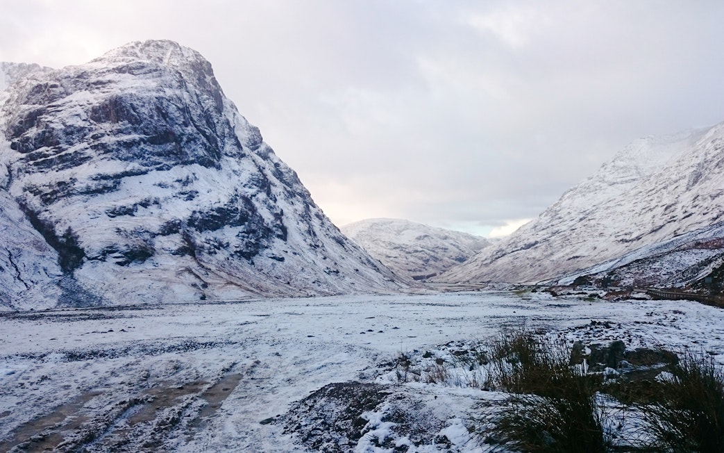 Snow-covered mountains in Glencoe, Scotland during winter.