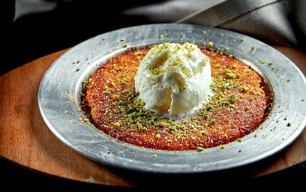 Traditional Turkish dessert with ice cream on a metal plate, featured on Sternschanze food tour.