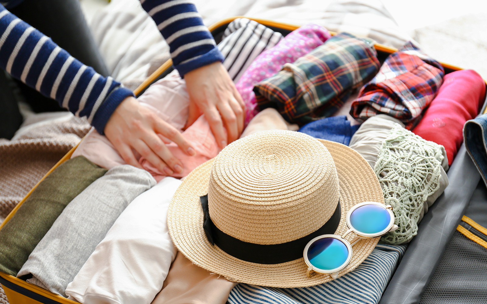 Open suitcase with neatly packed clothes and travel essentials for a trip.