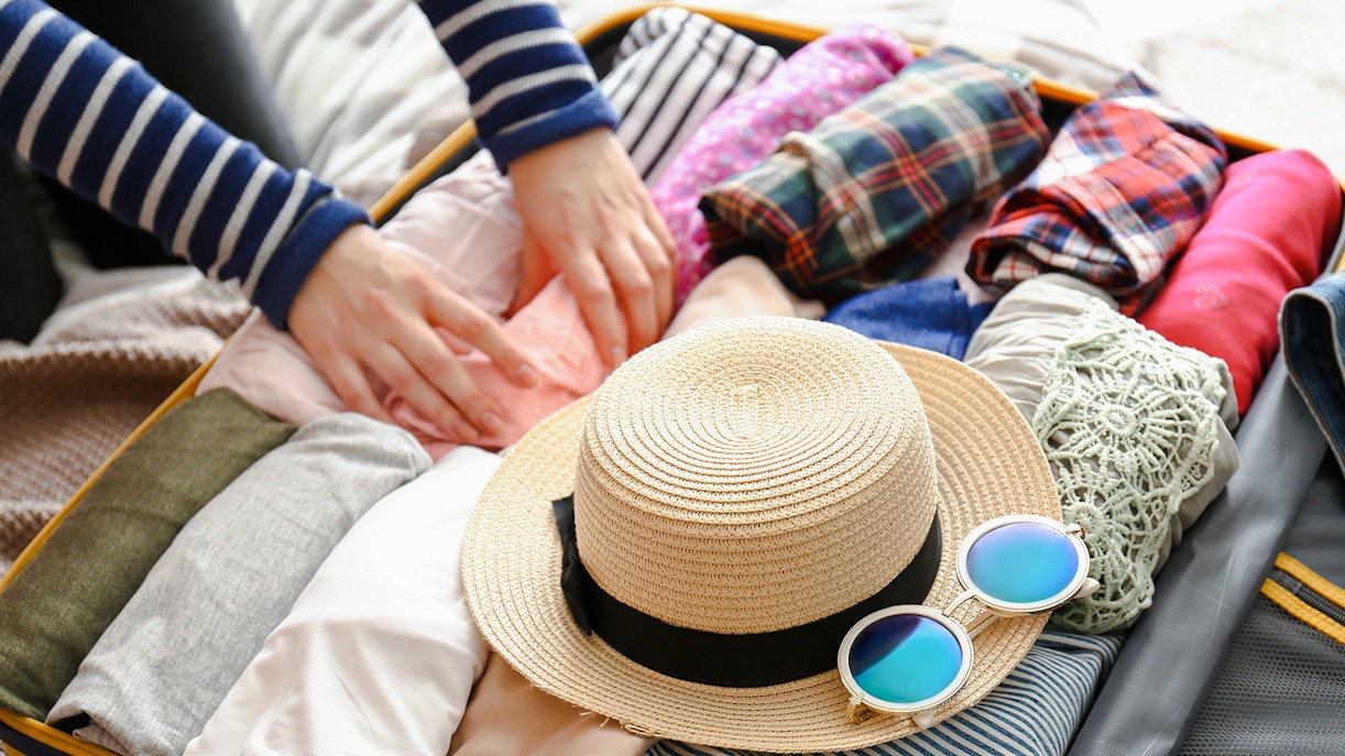 Open suitcase with neatly packed clothes and travel essentials for a trip.