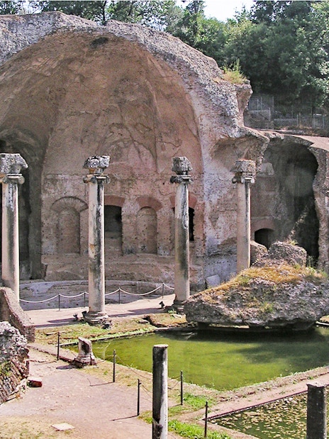 Ancient ruins and columns at Tivoli Villae, Italy, with a reflecting pool in the foreground.