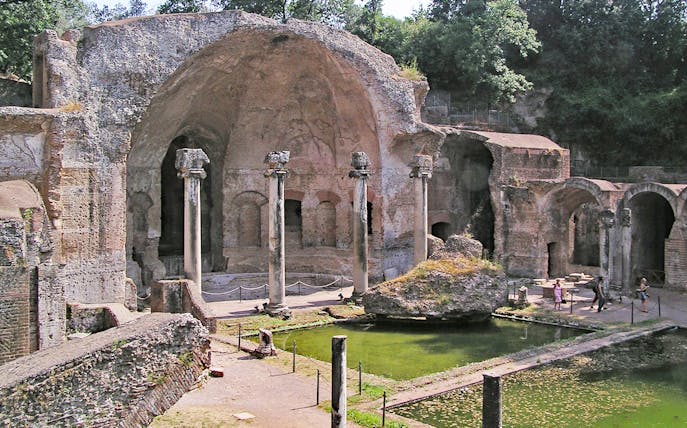Ancient ruins and columns at Tivoli Villae, Italy, with a reflecting pool in the foreground.