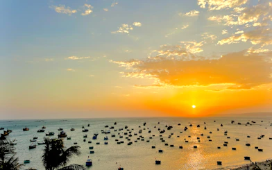 Boats on the water at sunset in Mui Ne, Vietnam, viewed from the shore.