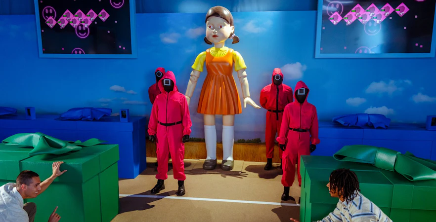 Participants reenact Squid Game scene with giant doll and guards at Netflix house in Dallas.