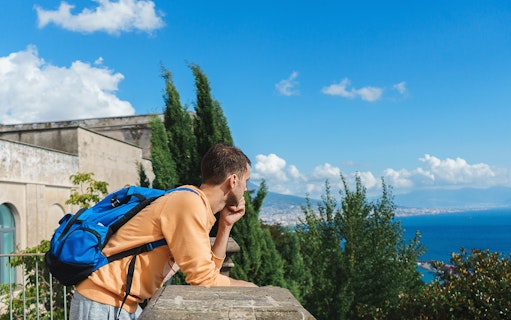 Man with backpack enjoying view of Naples coastline during Pedamentina trek.