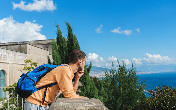 Man with backpack enjoying view of Naples coastline during Pedamentina trek.