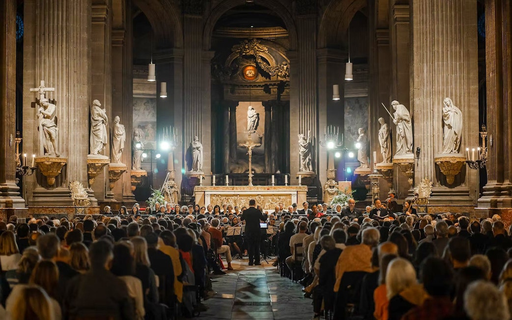 Orchestra performing in St Sulpice Church, Paris, with audience seated in the nave.