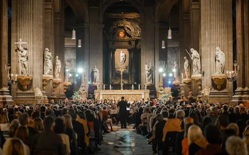 Orchestra performing in St Sulpice Church, Paris, with audience seated in the nave.
