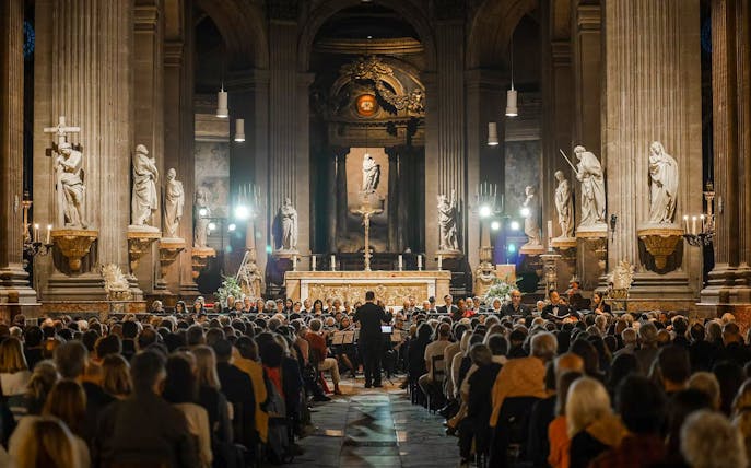 Orchestra performing in St Sulpice Church, Paris, with audience seated in the nave.