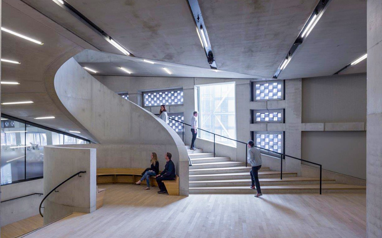 Tate Modern interior with visitors on a spiral staircase and modern architectural design.