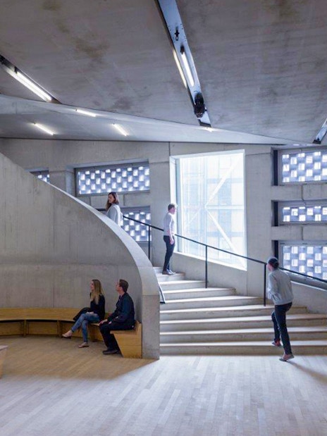 Tate Modern interior with visitors on a spiral staircase and modern architectural design.