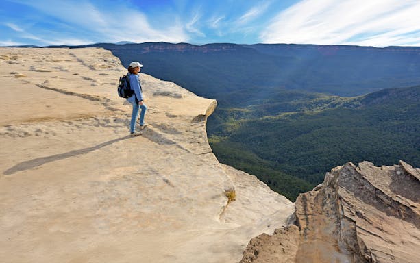 Woman standing on cliff edge overlooking Grose Valley, Blue Mountains.