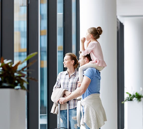 Family with luggage looking out window at Plaza Premium Lounge Rome.