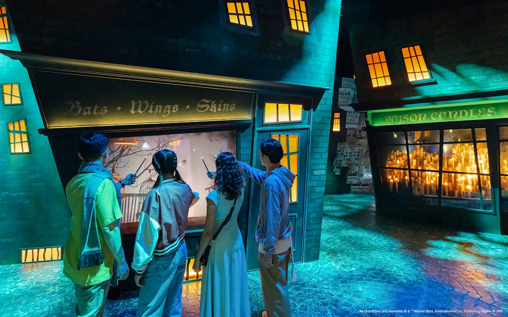 People exploring Diagon Alley shop displays with wands, Harry Potter Visions of Magic tour.