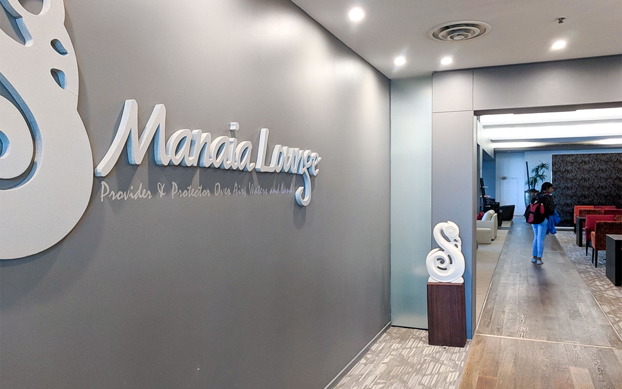 Plaza Premium Lounge entrance with seating area and decorative wall sign.