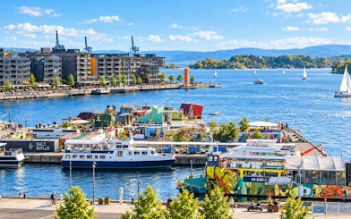 Oslo harbor view with colorful boats and waterfront buildings, part of a small-group walking tour.