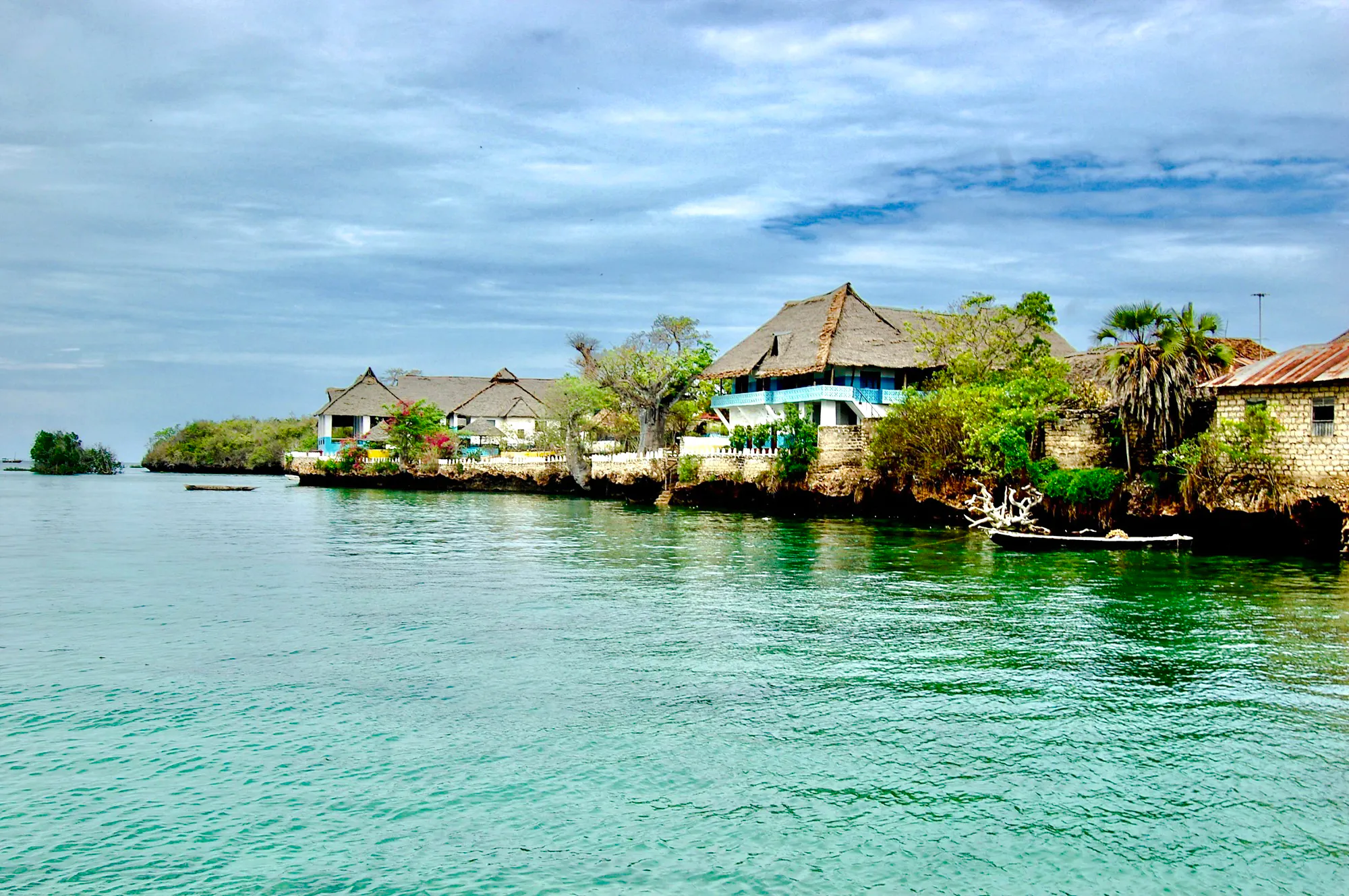 Coastal village view on Wasini Island with traditional thatched-roof houses by the water.