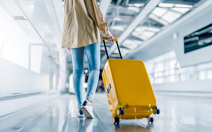 Woman walking with yellow suitcase at Incheon Airport.