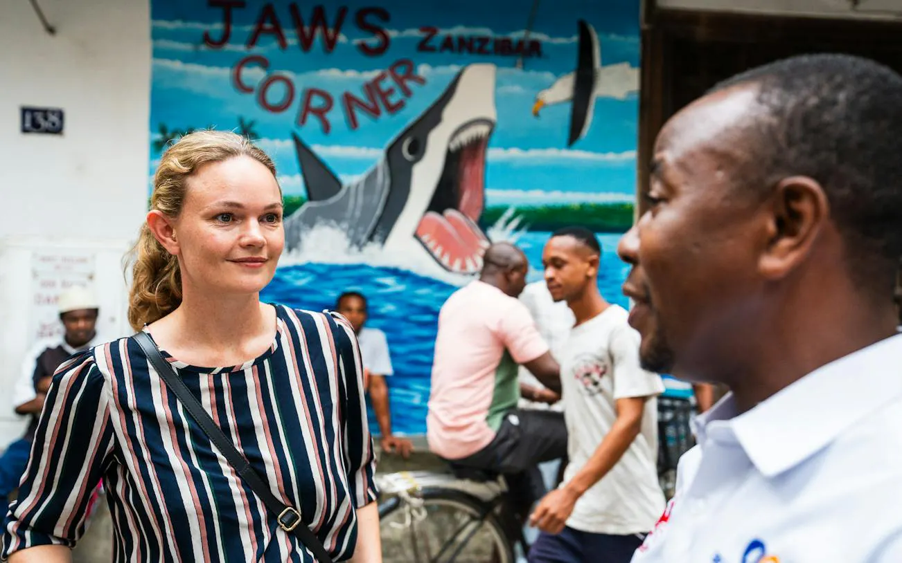 Tourists in Stone Town, Zanzibar, near Jaws Corner mural during walking tour.