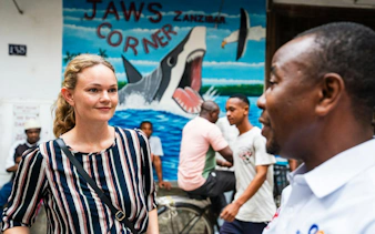 Tourists in Stone Town, Zanzibar, near Jaws Corner mural during walking tour.