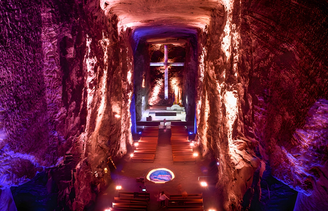 Salt Cathedral of Zipaquirá interior with illuminated cross and seating.