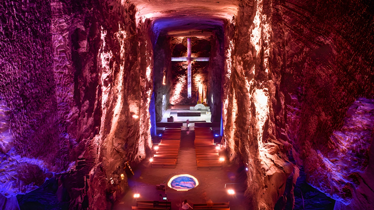 Salt Cathedral of Zipaquirá interior with illuminated cross and seating.