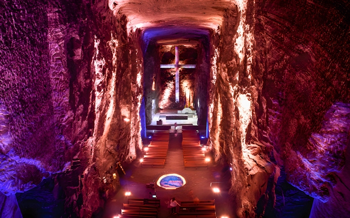 Salt Cathedral of Zipaquirá interior with illuminated cross and seating.