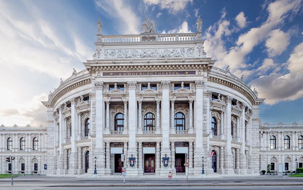 Burgtheater exterior with ornate columns and statues, Vienna, Austria.