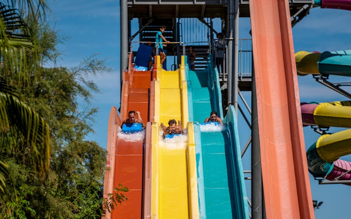 Visitors enjoying colorful water slides at Isla Mágica theme park.