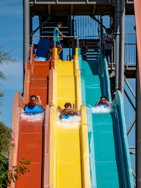 Visitors enjoying colorful water slides at Isla Mágica theme park.