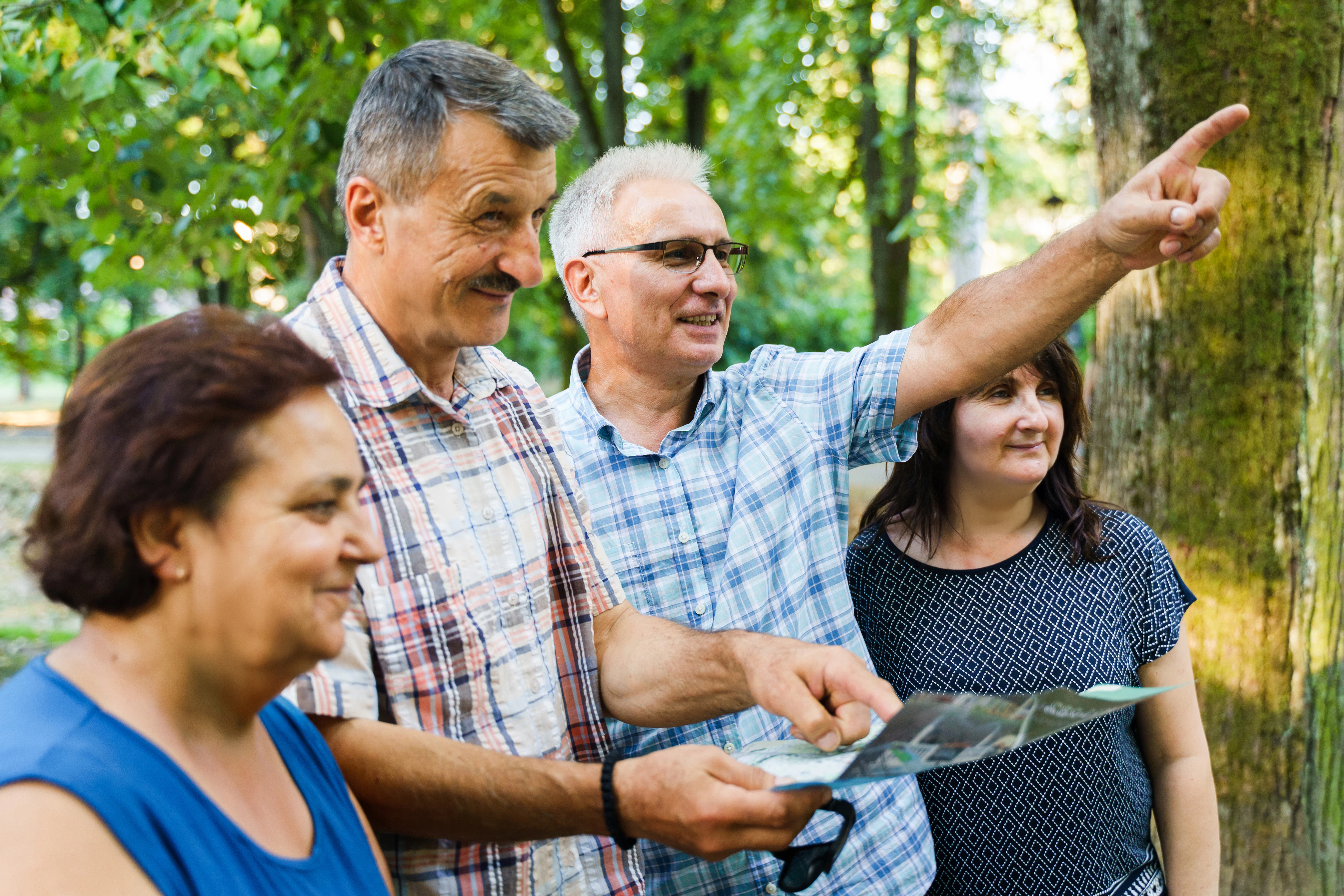 Tour guide pointing out landmarks to tourists in a forest setting.
