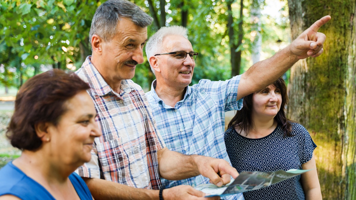 Tour guide pointing out landmarks to tourists in a forest setting.