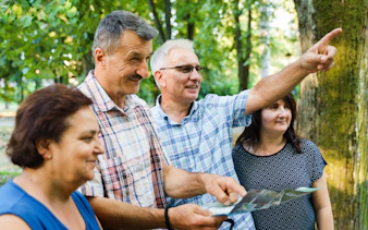 Tour guide pointing out landmarks to tourists in a forest setting.