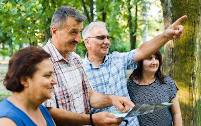 Tour guide pointing out landmarks to tourists in a forest setting.