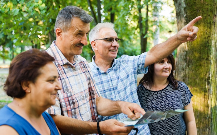 Tour guide pointing out landmarks to tourists in a forest setting.