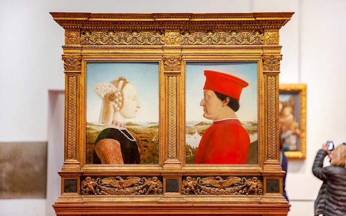 Portraits of a man and woman in ornate frames at Uffizi Gallery, Florence.