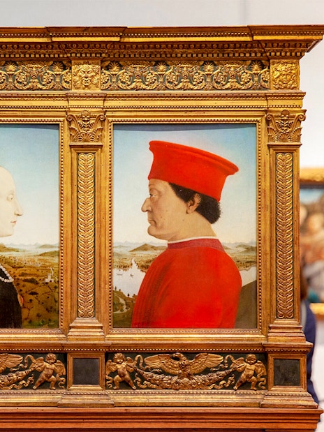 Portraits of a man and woman in ornate frames at Uffizi Gallery, Florence.