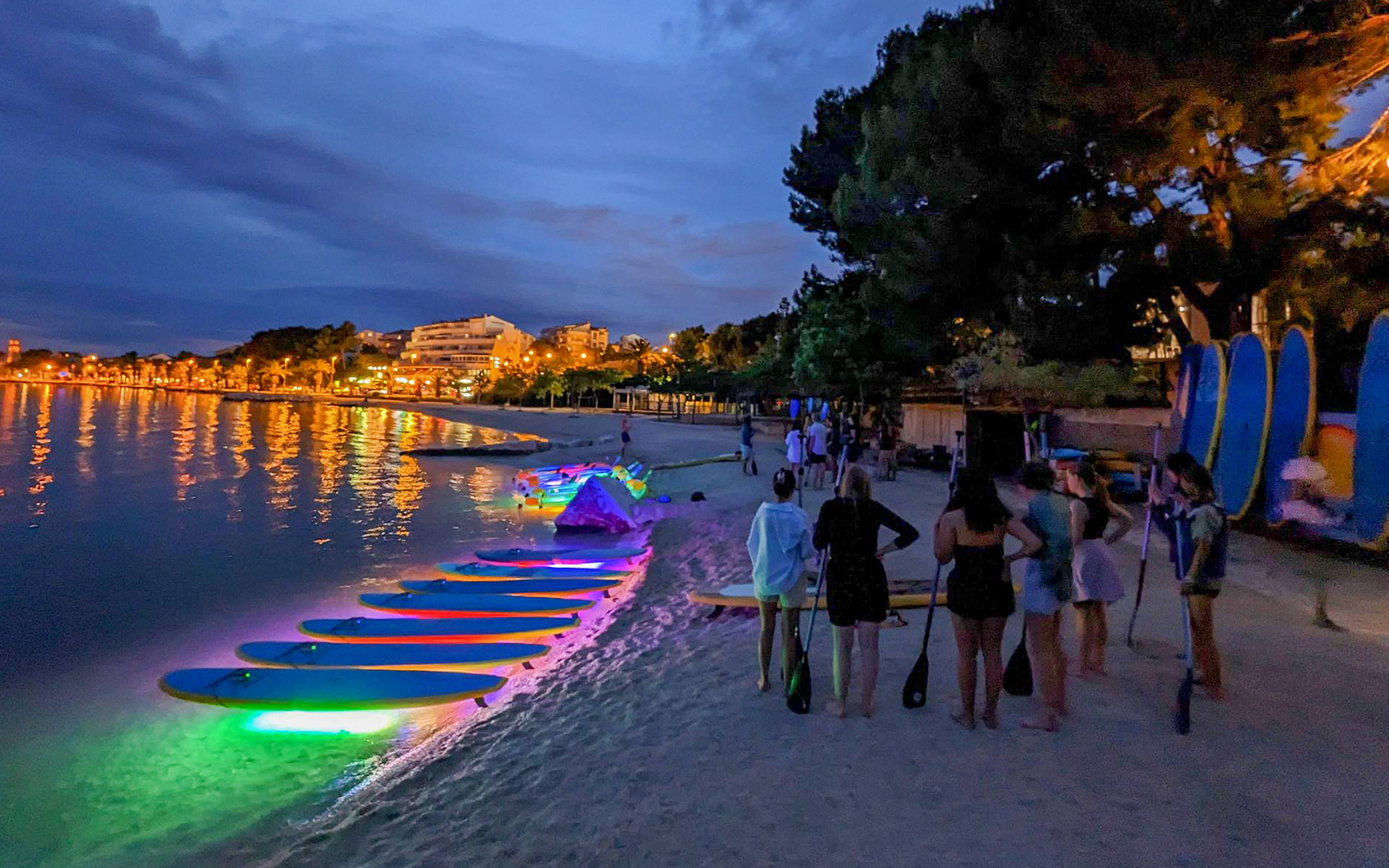 Paddleboards with glowing lights on a beach at night, SUP Glow Tour in Split.