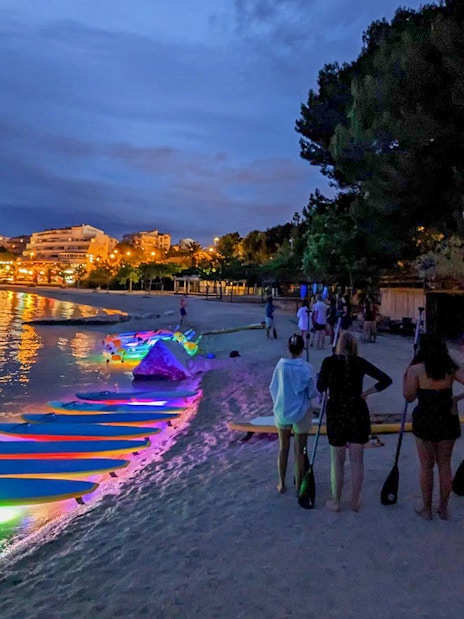 Paddleboards with glowing lights on a beach at night, SUP Glow Tour in Split.