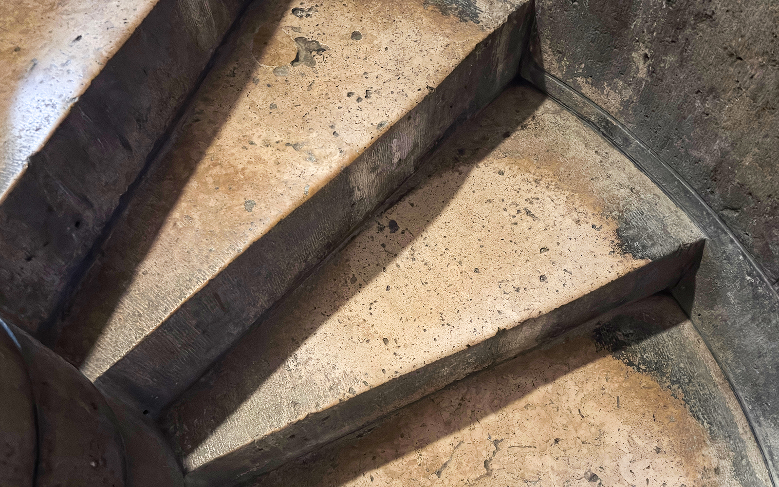 Stone spiral staircase steps inside an ancient building.